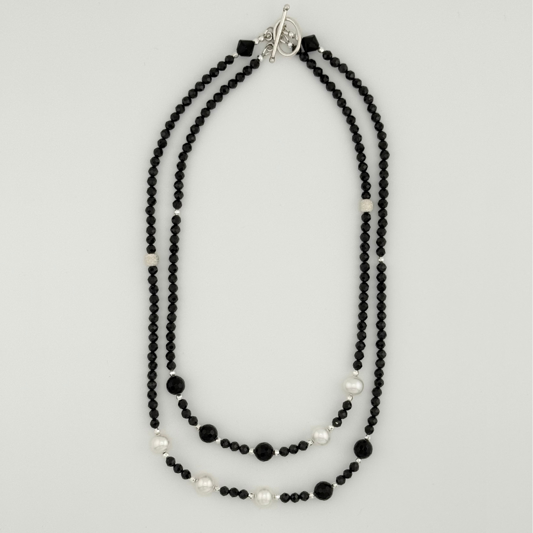 Pearl, Spinel, Onyx, and Sterling Silver flatlay on white background