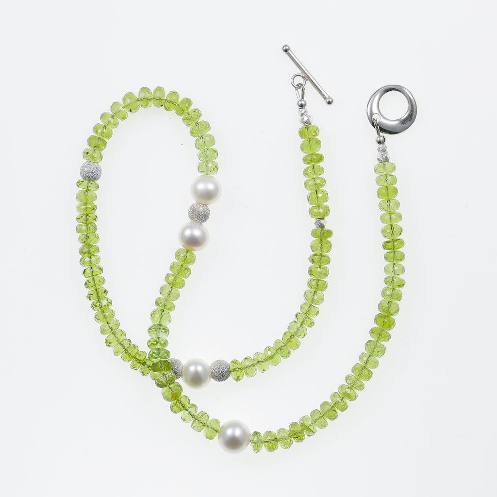 Peridot, Pearl, and Sterling Silver Necklace artistic flatlay on white background