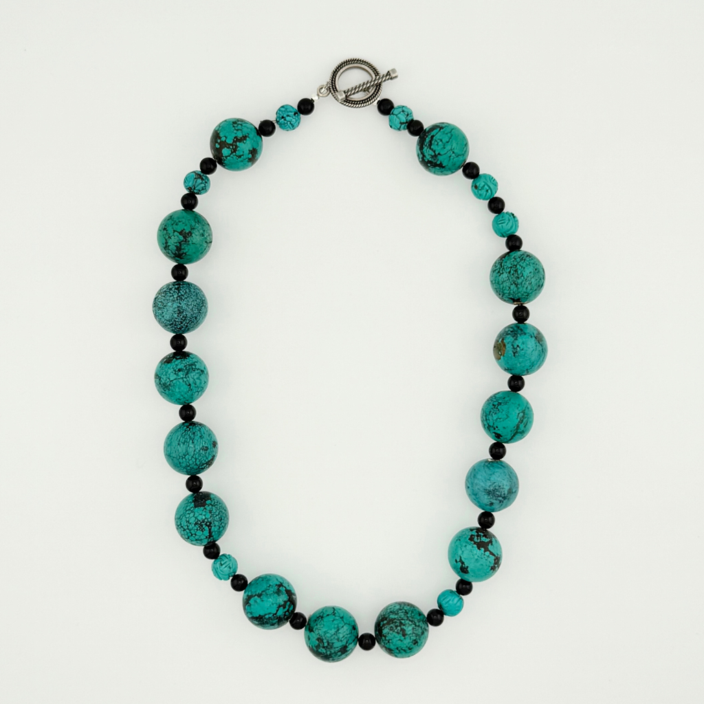 Turquoise, Onyx, and Silver Necklace flatlay on white background